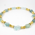 A necklace of green and blue beads with gold accents.