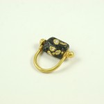 A black and gold ring with a small gold bead.