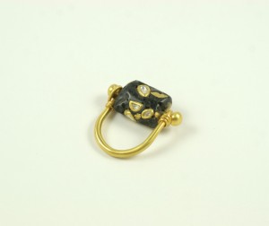 A black and gold ring with a small gold bead.