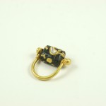 A gold ring with black and yellow beads on it.