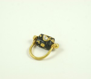 A gold ring with black and yellow beads on it.