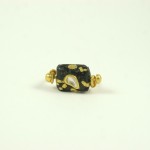 A black and gold bead ring with a pearl in the middle.