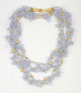 A necklace of three strands with gold beads and blue glass flowers.