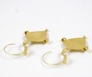 A pair of gold earrings with a small piece of metal.