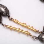 A close up of the gold and silver beads on a necklace