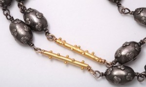 A close up of the gold and silver beads on a necklace