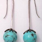 A pair of turquoise earrings with long silver stems.