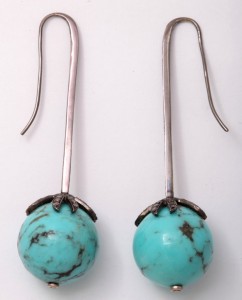 A pair of turquoise earrings with long silver stems.