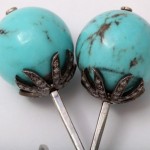 A pair of turquoise lollipops with diamonds on top.