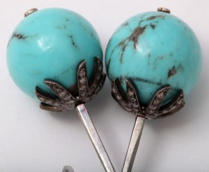 A pair of turquoise lollipops with diamonds on top.