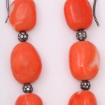 A pair of earrings with orange beads and silver balls.