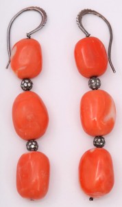 A pair of earrings with orange beads and silver balls.