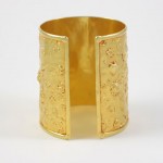 A gold cuff bracelet with a floral design.