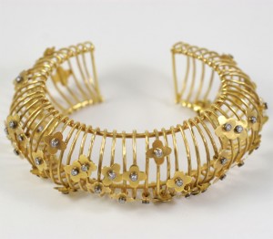 A gold bracelet with lots of small flowers.
