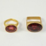 A gold ring and a red stone on top of a table.