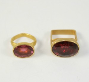 A gold ring and a red stone on top of a table.