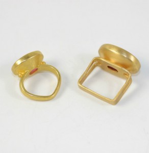 A pair of gold rings with one being a square and the other is an oval.
