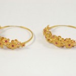 A pair of gold earrings with red stones.