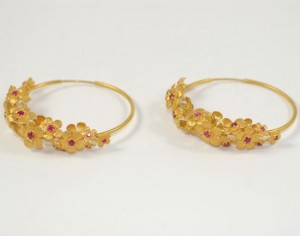 A pair of gold earrings with red stones.