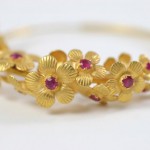 A gold bracelet with flowers and rubies.