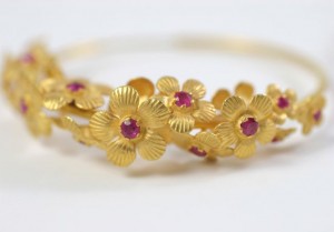 A gold bracelet with flowers and rubies.
