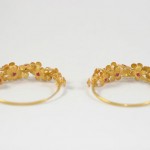 A pair of gold bracelets with flowers on them.