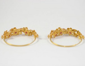 A pair of gold bracelets with flowers on them.