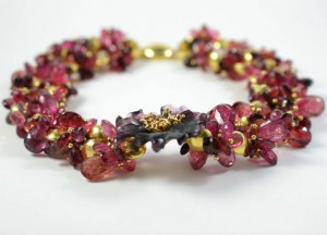 A close up of a bracelet with red and gold beads