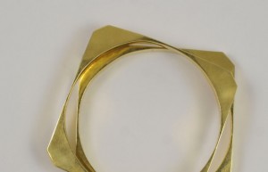 A gold bracelet is shown on top of the table.