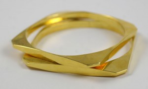 A gold bracelet is shown on top of the table.
