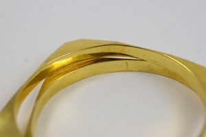 A close up of the side of two gold bracelets
