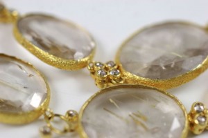 A close up of the gold and crystal necklace.