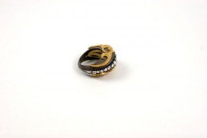 A gold and black ring with white stones on it.