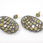 A pair of earrings with gold and black diamonds.