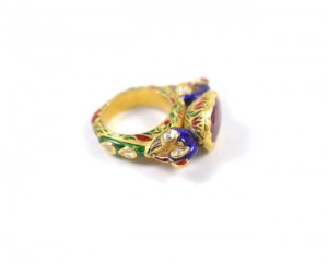 A gold ring with a purple stone on it's side.