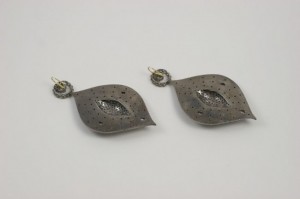 A pair of earrings with a metal leaf design.