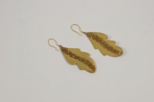 A pair of gold leaf earrings on a white surface.