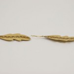 A pair of wooden feathers with a chain on them.