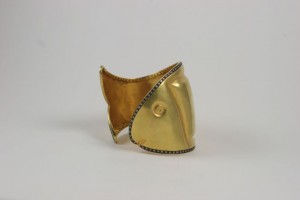 A gold plated metal mask with black and white diamond accents.