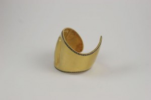 A gold cuff with black and white stones on it.