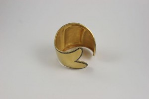 A gold plated bracelet with a design on it.
