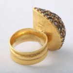 A gold ring with a diamond on it's side.