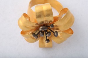 A gold flower with black tips on top of it.