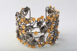 A metal bracelet with yellow flowers on it.