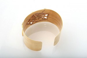 A gold bracelet with a cross on it.