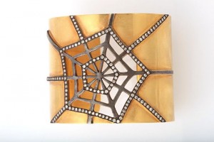 A gold and silver spider web with white stones.