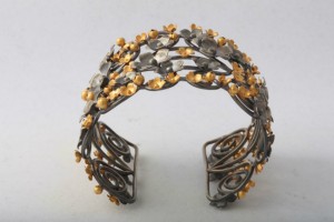 A metal bracelet with gold leaves on it.