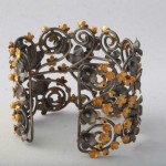 A metal bracelet with yellow flowers on it.