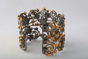 A metal bracelet with yellow flowers on it.