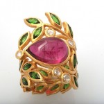 A gold ring with leaves and a pink stone.